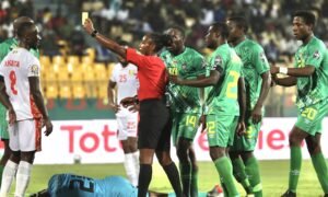 Referee Salima Rhadia Mukansanga of Rwanda shows a yellow card to Guinea captain Naby Keita