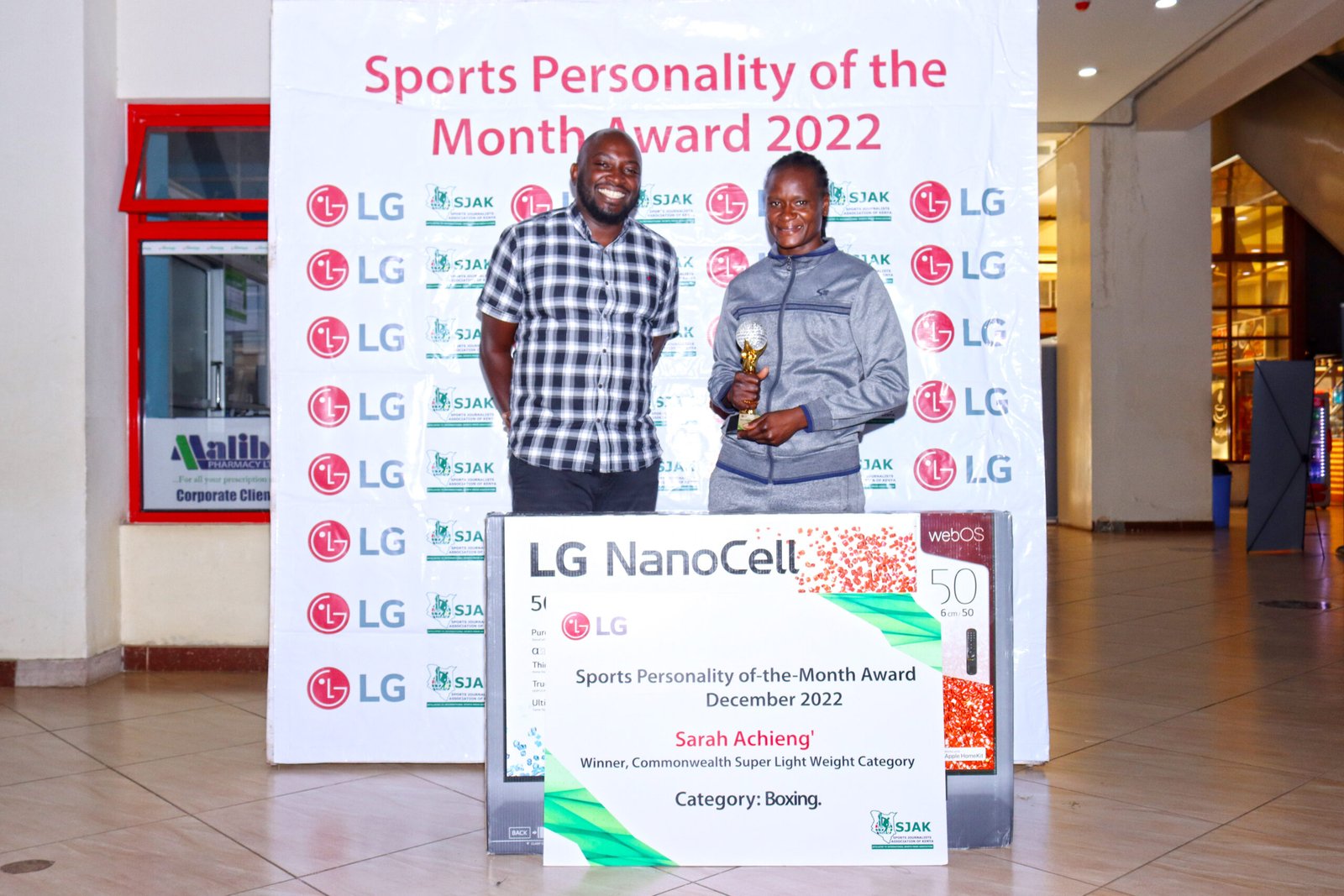 Sarah Achieng receives her rewards from LGs William Kamore.JPG scaled